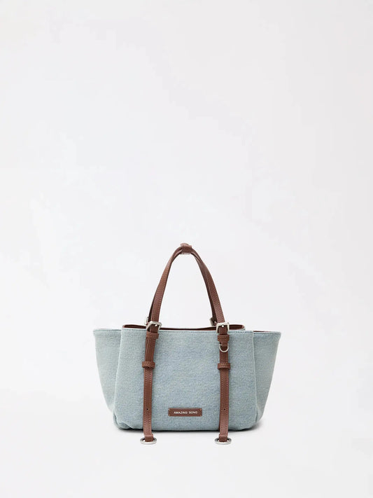 A small donut-shaped top-grain leather tote carried on the shoulder in daylight