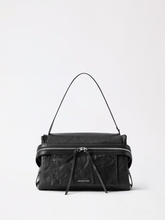 Cheese roll briefcase in tan top-grain leather standing upright on a desk with a laptop beside it