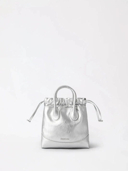 A slouchy silver leather hobo bag with soft draped curves resting on a neutral linen surface