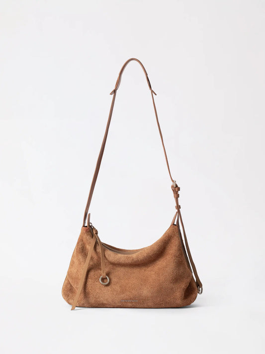 Large suede donut hobo bag in soft taupe hanging against a neutral studio backdrop
