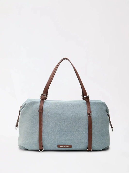 The Donut - Travel Boston weekender in blue fabric and cowhide on a wooden bench