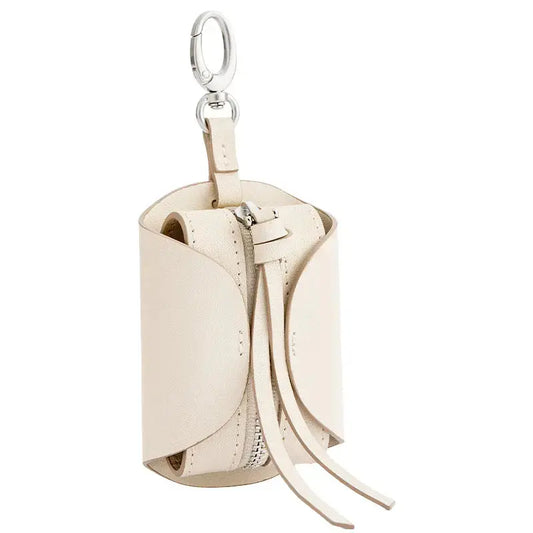 A small cheese roll shaped leather headphone bag in warm tan resting on a linen surface