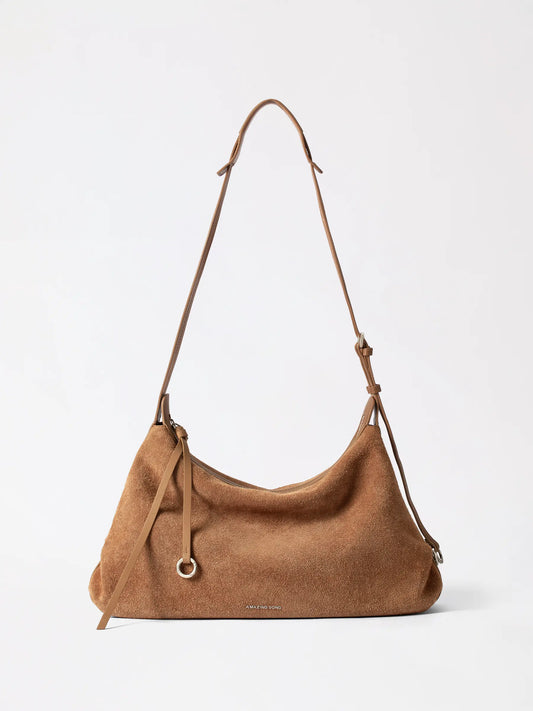 A round suede donut hobo bag in soft taupe leather on a table