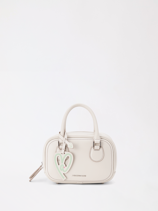 Small toast-shaped top-grain leather bag held in one hand against a neutral background