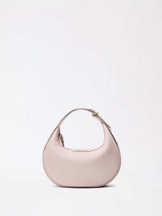A small half-moon leather bag in warm caramel resting on a linen surface