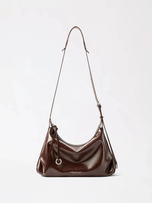 A medium top-grain cowhide leather Boston bag standing upright on a wooden table
