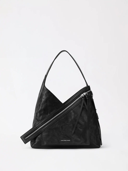 A rounded cheese roll shaped leather shoulder bag resting on a wooden chair