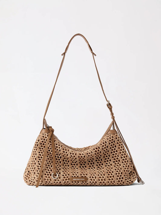 The large woven leather donut hobo bag in warm tan shown from the side to display its slouchy crescent shape