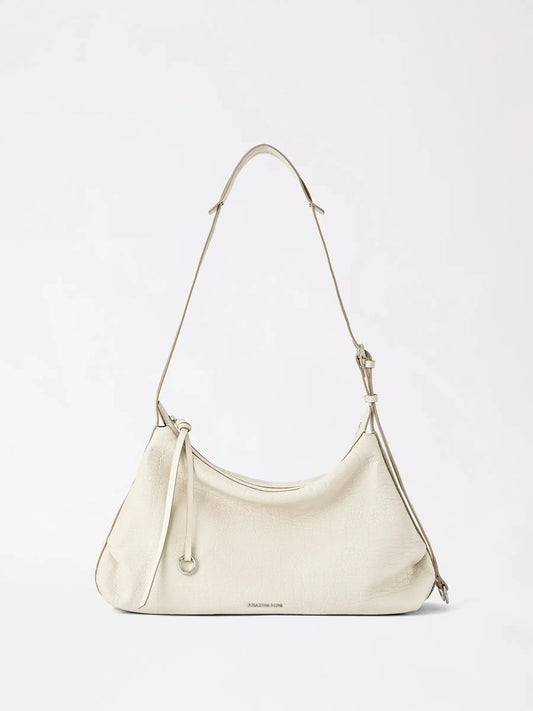 A large donut-shaped hobo bag in top-grain cowhide resting on linen