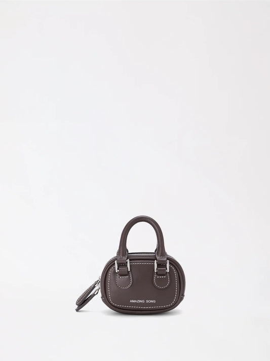 A tiny toast-shaped cowhide mini bag resting on a cafe table by a cup