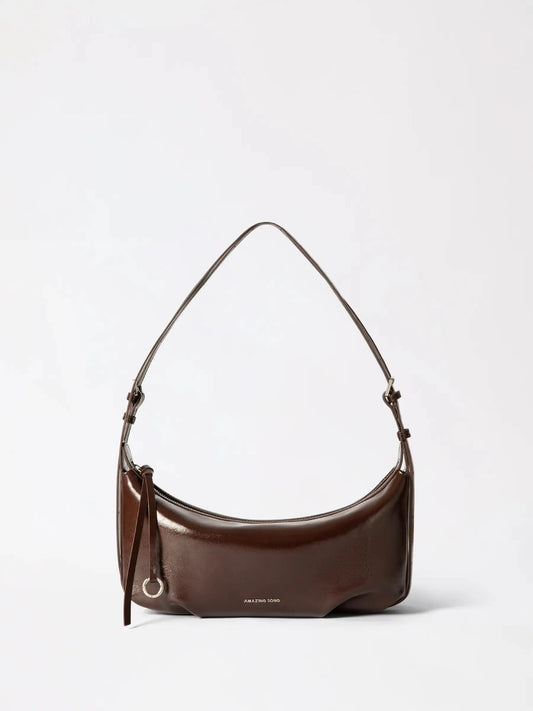 A small croissant-shaped leather bag in warm tan leather