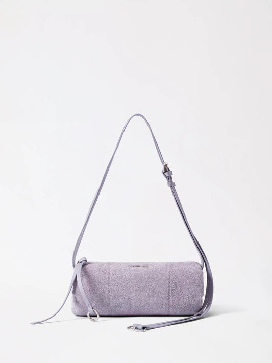 A donut-shaped suede pen holder bag in soft taupe sitting on a wooden desk