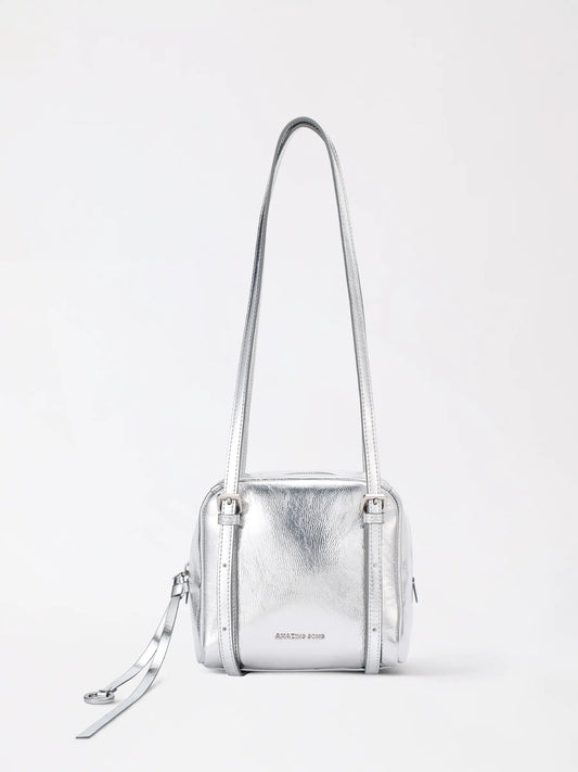 The donut square bag in smooth tan top-grain leather standing upright on a wooden table
